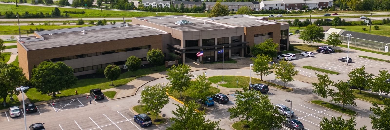 Aerial view of the Jessamine Career & Technology Center, with flagpoles at the main entrance and parking beside the highway